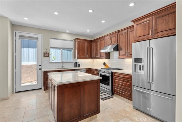 kitchen featuring tasteful backsplash, a center island, sink, light stone countertops, and high quality appliances