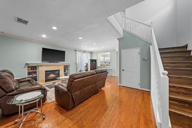 living room featuring a fireplace, crown molding, and hardwood / wood-style floors