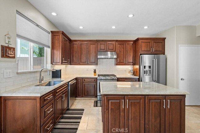 kitchen featuring appliances with stainless steel finishes, sink, decorative backsplash, and a center island