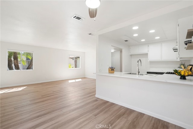 kitchen with kitchen peninsula, white cabinetry, sink, and light wood-type flooring