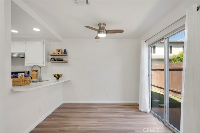 unfurnished dining area featuring light hardwood / wood-style floors, sink, and ceiling fan