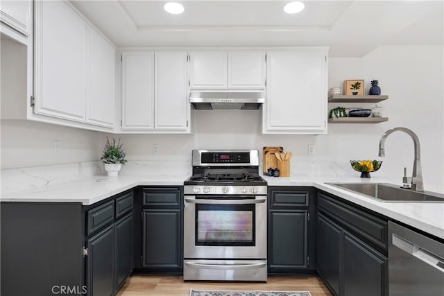 kitchen featuring sink, white cabinetry, stainless steel appliances, light stone counters, and light hardwood / wood-style flooring