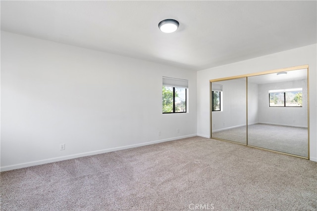 unfurnished bedroom featuring multiple windows, a closet, and carpet floors