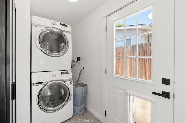 laundry area featuring light tile patterned flooring and stacked washer / drying machine