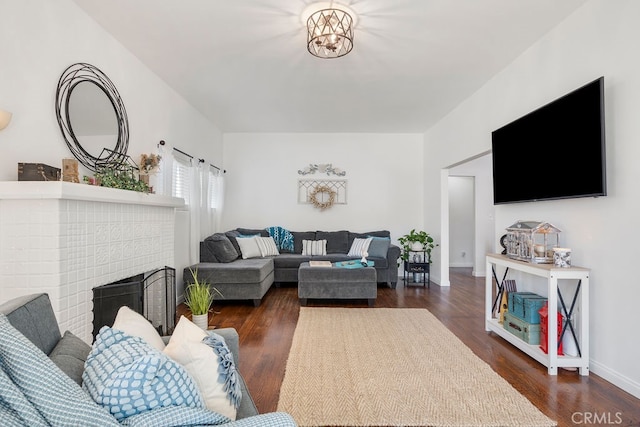 living room featuring a brick fireplace and dark hardwood / wood-style floors