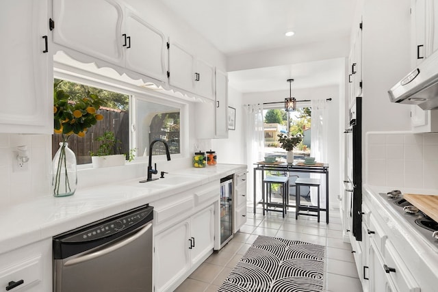 kitchen with sink, beverage cooler, white cabinetry, stainless steel appliances, and decorative backsplash