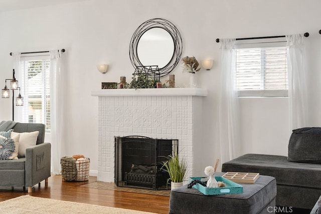 living room with hardwood / wood-style flooring, a wealth of natural light, and a tile fireplace