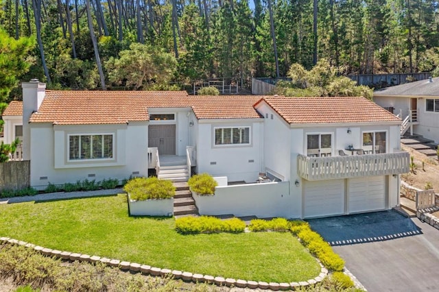 view of front of home with a garage, a front yard, and a balcony