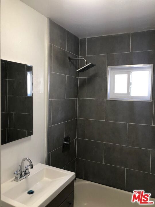 bathroom with tiled shower / bath combo and vanity