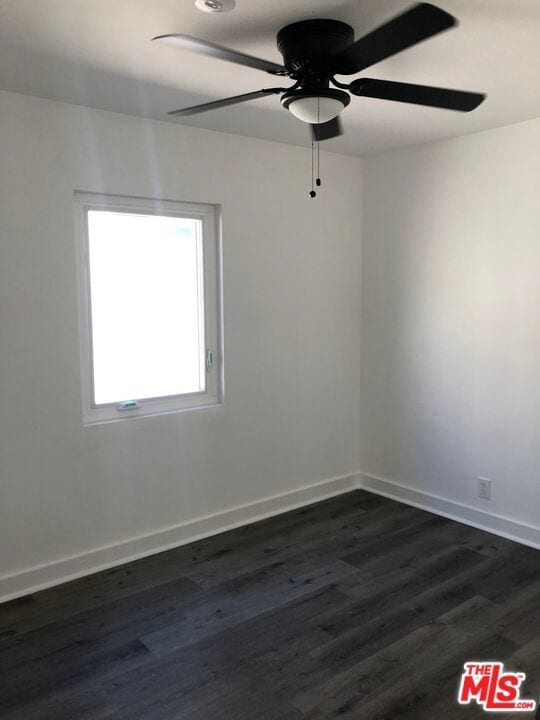 empty room featuring ceiling fan and dark hardwood / wood-style floors