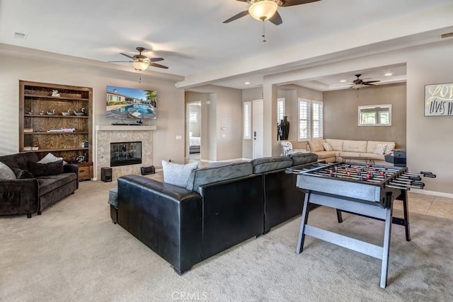 carpeted living room with ceiling fan and a tile fireplace