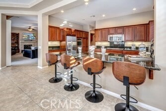 kitchen featuring a kitchen bar, white fridge, wall oven, light tile patterned floors, and ceiling fan