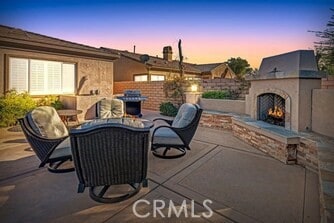 patio terrace at dusk featuring exterior fireplace