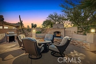 patio terrace at dusk featuring an outdoor fireplace