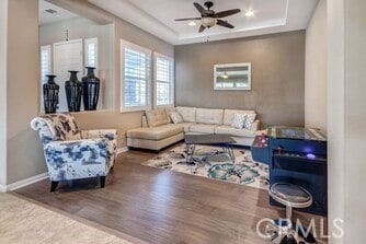 living room with ceiling fan, a raised ceiling, and hardwood / wood-style flooring