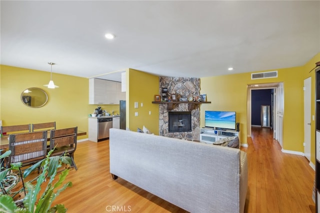 living room featuring a stone fireplace and light wood-type flooring