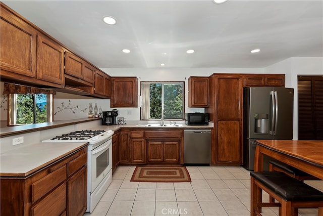 kitchen featuring sink, light tile patterned floors, stainless steel appliances, and plenty of natural light