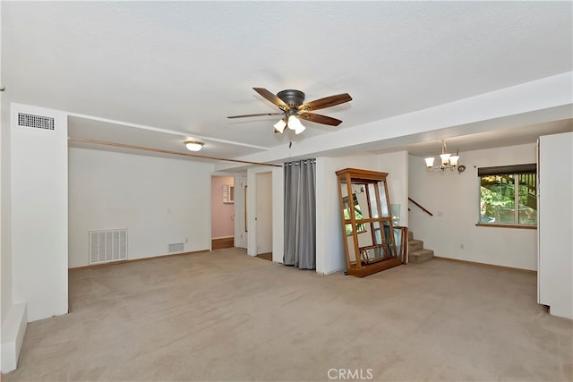 spare room with a textured ceiling, ceiling fan with notable chandelier, and light colored carpet