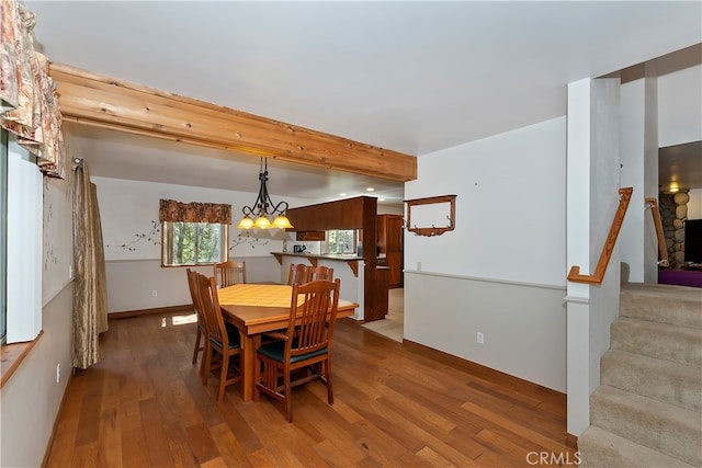 dining room featuring beamed ceiling, hardwood / wood-style floors, and a chandelier