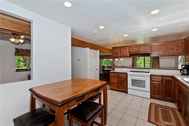 kitchen with recessed lighting, white gas stove, light countertops, and light tile patterned floors
