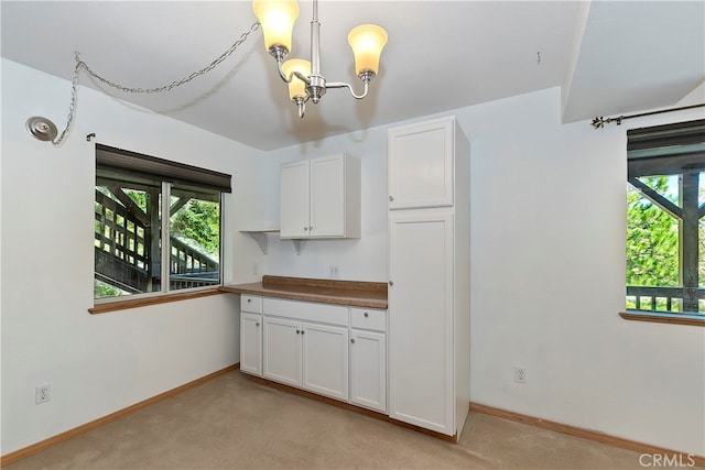 kitchen featuring a notable chandelier, hanging light fixtures, light carpet, and white cabinets