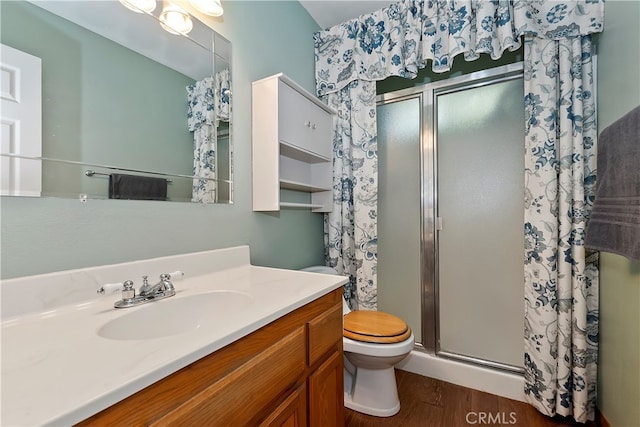 bathroom featuring hardwood / wood-style flooring, vanity, toilet, and a shower with shower door