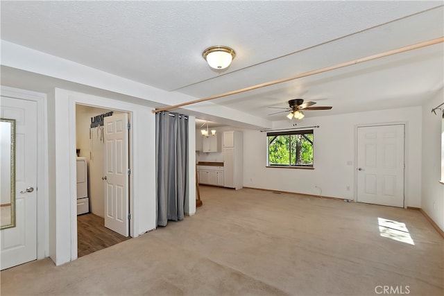 carpeted empty room with washer / clothes dryer, ceiling fan, and a textured ceiling