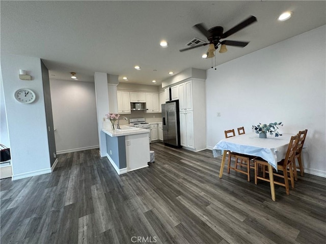 kitchen featuring white cabinets, kitchen peninsula, dark wood-type flooring, and appliances with stainless steel finishes