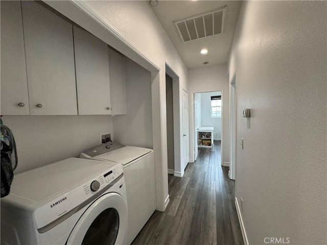 washroom featuring cabinets, dark wood-type flooring, and washing machine and clothes dryer