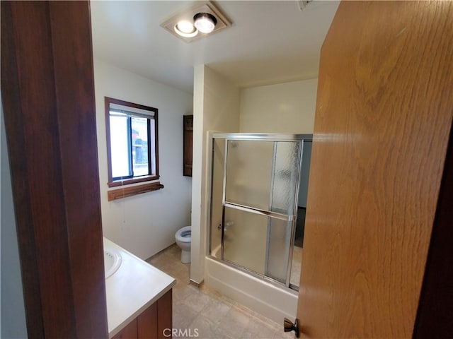 full bathroom featuring vanity, bath / shower combo with glass door, and toilet