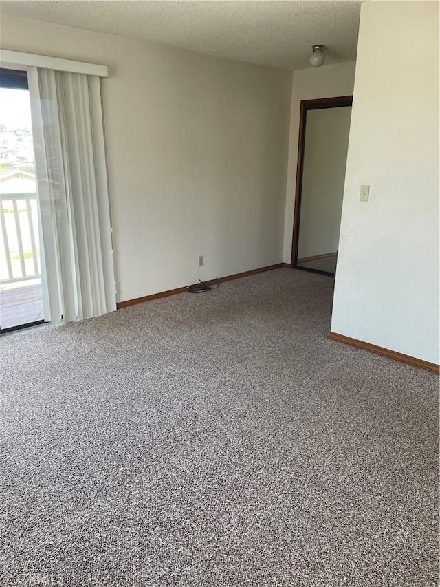 carpeted empty room featuring a textured ceiling