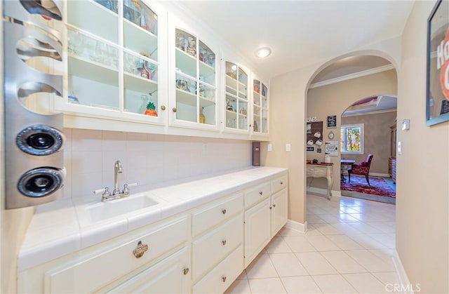 46469 Wallu Ln, Ahwahnee, CA 93601 - bar featuring light tile patterned floors, ornamental molding, decorative backsplash, a sink, and arched walkways