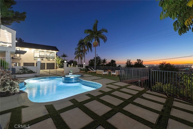 pool at dusk featuring a patio and an in ground hot tub