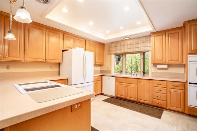 kitchen with a tray ceiling, sink, decorative light fixtures, and white appliances