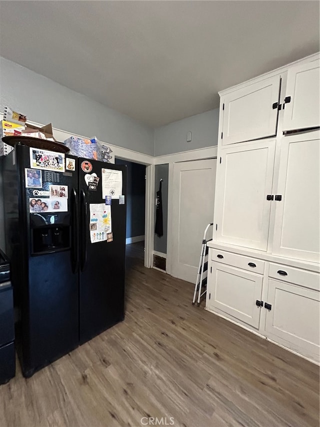 kitchen featuring white cabinets, black fridge, and dark hardwood / wood-style flooring