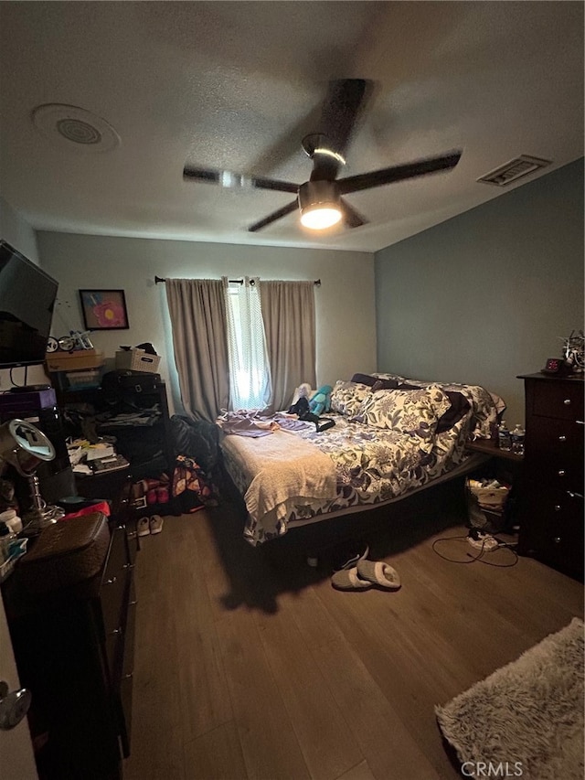 bedroom featuring ceiling fan, hardwood / wood-style flooring, and a textured ceiling