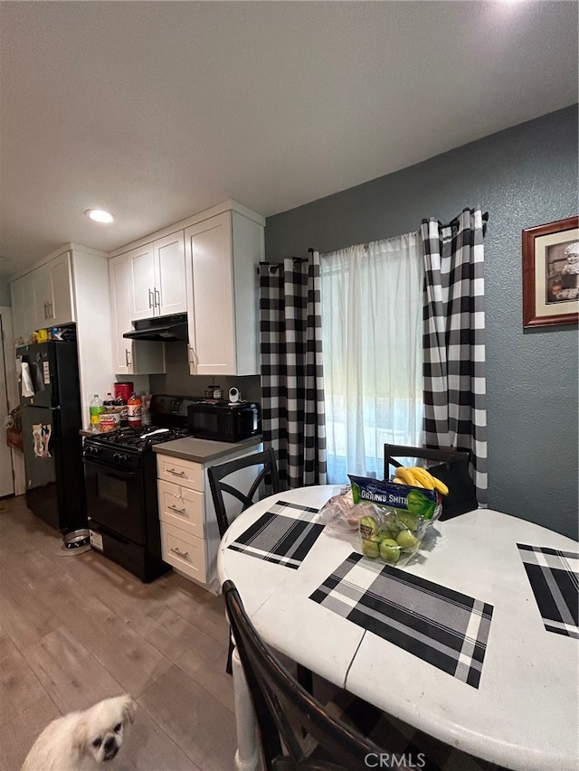 kitchen with white cabinets, light hardwood / wood-style floors, and black appliances