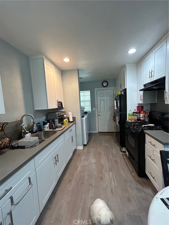 kitchen featuring white cabinets, sink, black appliances, washer / dryer, and light hardwood / wood-style floors