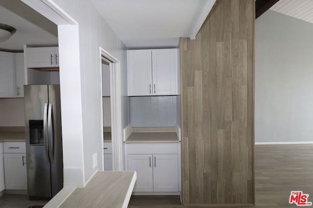 kitchen featuring wood-type flooring, stainless steel refrigerator with ice dispenser, lofted ceiling, and white cabinetry