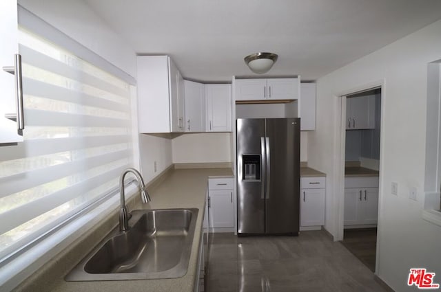 kitchen featuring stainless steel fridge, sink, and white cabinetry