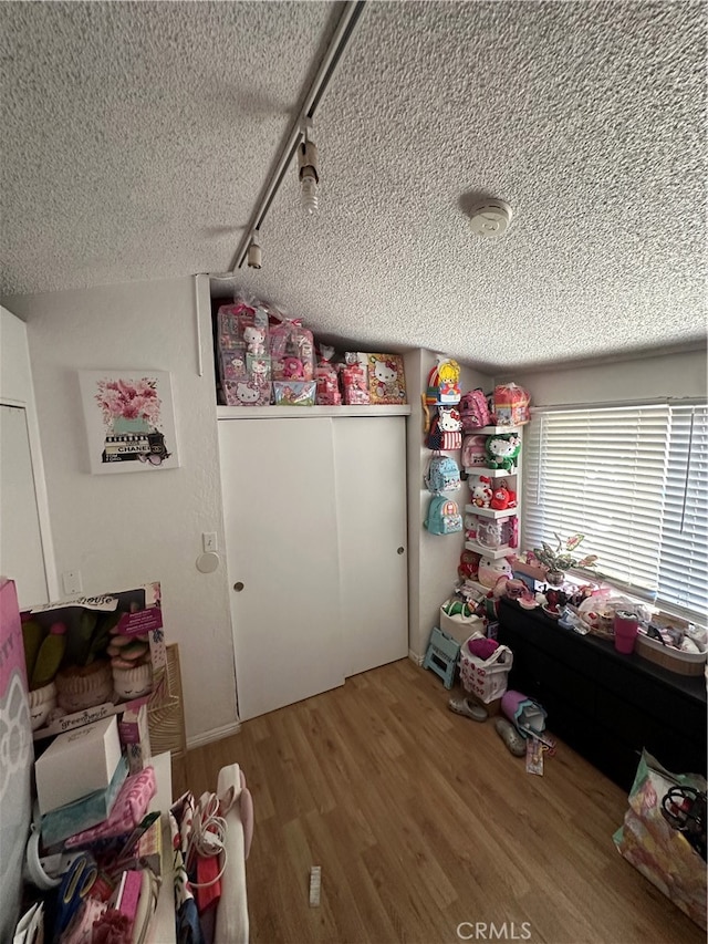 bedroom with a textured ceiling, rail lighting, and hardwood / wood-style floors