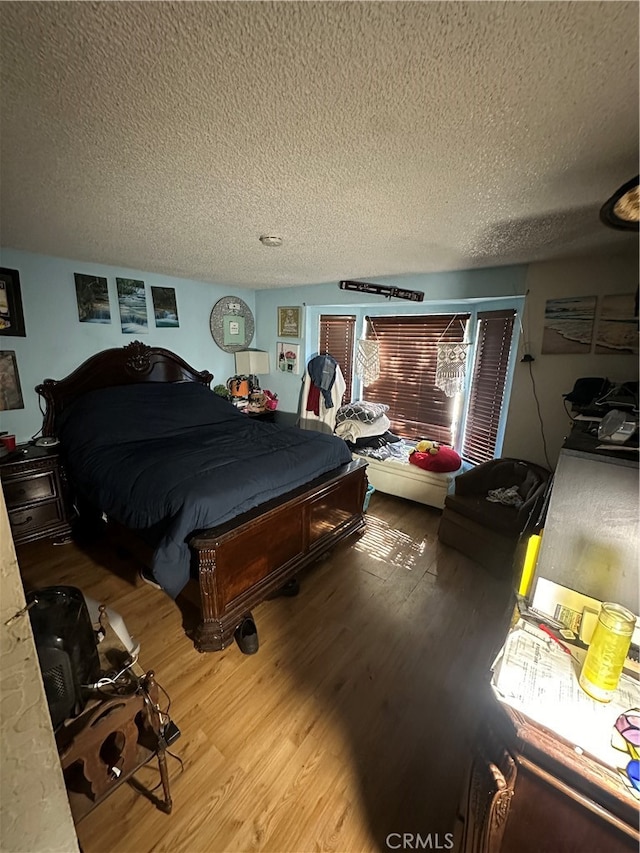 bedroom with a textured ceiling and wood-type flooring