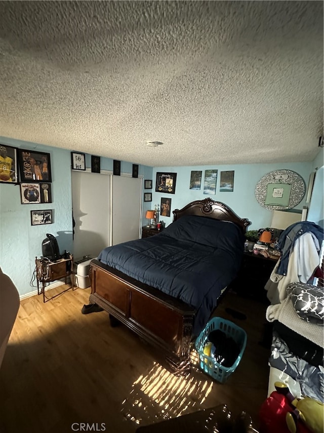 bedroom with a textured ceiling and hardwood / wood-style floors