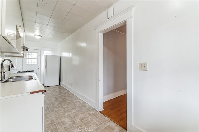 kitchen with white cabinets, white refrigerator, light wood-type flooring, and sink