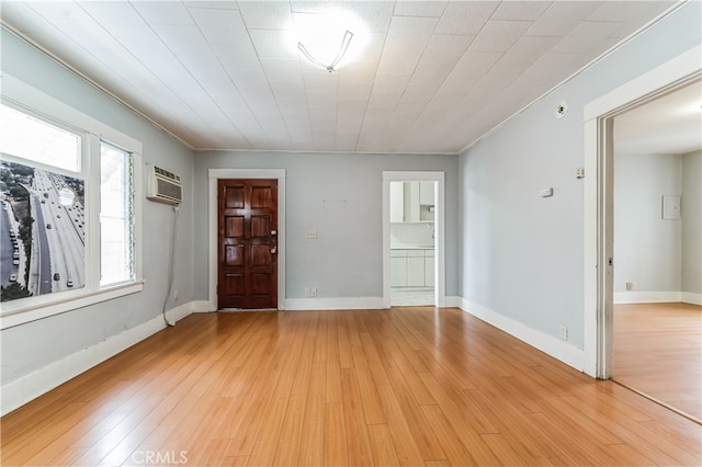 foyer with light hardwood / wood-style flooring, ornamental molding, and a wall unit AC