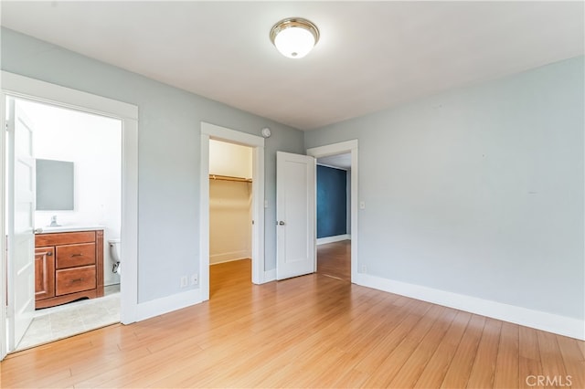 unfurnished bedroom with sink, a closet, light hardwood / wood-style floors, and a walk in closet