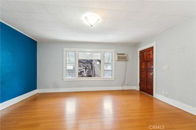 empty room with ornamental molding, light hardwood / wood-style floors, and a wall unit AC