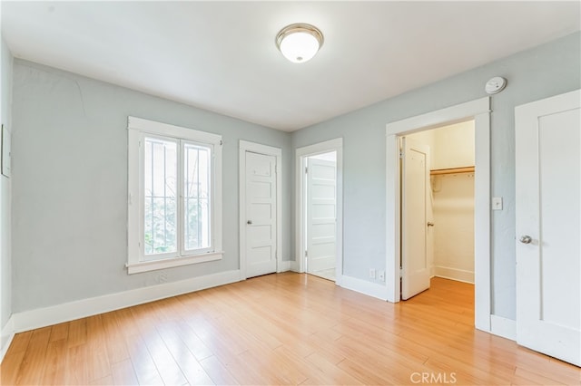 unfurnished bedroom featuring light hardwood / wood-style floors and a walk in closet