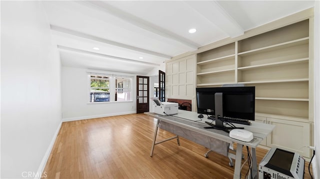 home office featuring light wood-type flooring and beamed ceiling