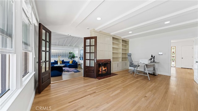 entrance foyer featuring a brick fireplace, light wood-type flooring, vaulted ceiling with beams, and french doors